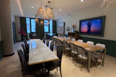 Salle de réunion avec une grande table en bois, entourée de fauteuils rembourrés, éclairée par une lampe et une fenêtre.