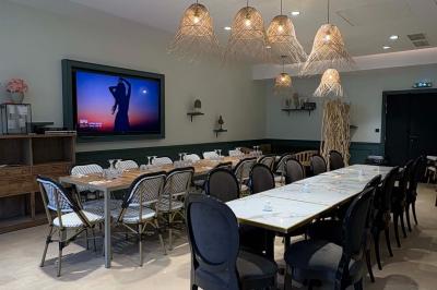 Salle de réunion avec une grande table en bois, entourée de fauteuils rembourrés, éclairée par une lampe et une fenêtre.