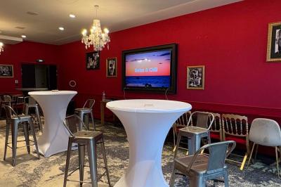 Salle de réunion avec une grande table en bois, entourée de fauteuils rembourrés, éclairée par une lampe et une fenêtre.