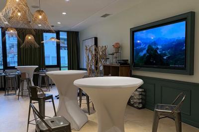 Salle de réunion avec une grande table en bois, entourée de fauteuils rembourrés, éclairée par une lampe et une fenêtre.