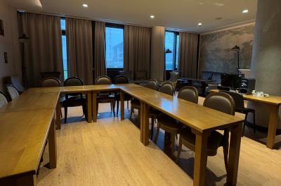 Salle de réunion avec une grande table en bois, entourée de fauteuils rembourrés, éclairée par une lampe et une fenêtre.