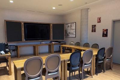 Salle de réunion avec une grande table en bois, entourée de fauteuils rembourrés, éclairée par une lampe et une fenêtre.