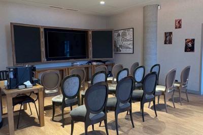 Salle de réunion avec une grande table en bois, entourée de fauteuils rembourrés, éclairée par une lampe et une fenêtre.