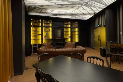 Salle de réunion avec une grande table en bois, entourée de fauteuils rembourrés, éclairée par une lampe et une fenêtre.