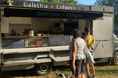 Façade d'un château en briques rouges et pierre claire avec tourelles, sous un ciel bleu partiellement nuageux.