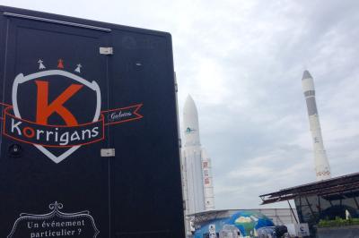 Façade d'un château en briques rouges et pierre claire avec tourelles, sous un ciel bleu partiellement nuageux.