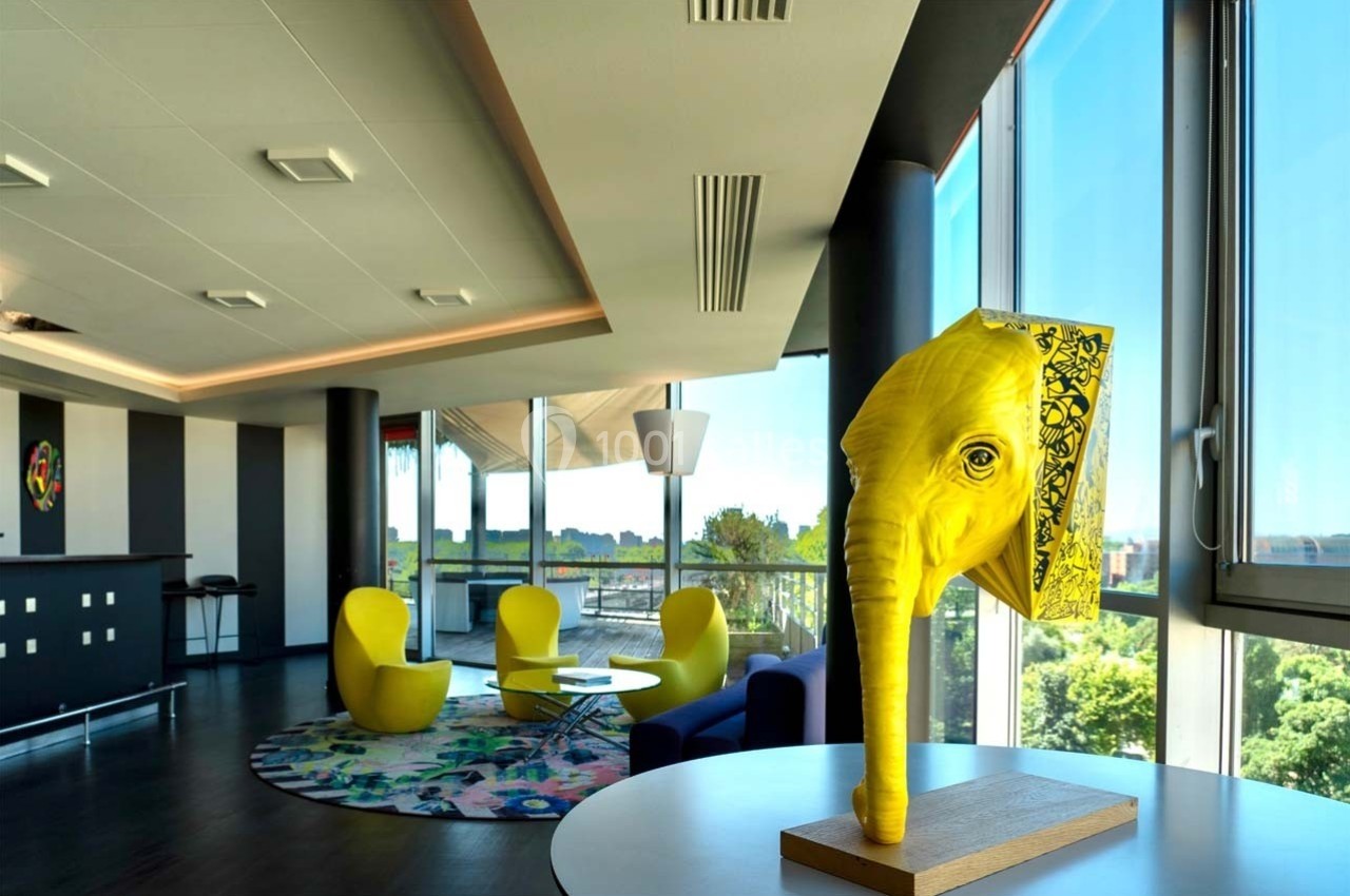 Location salle Caluire-et-Cuire (Rhône) - Le Belvédère #2 Sculpture jaune en forme de tête d'éléphant sur une table dans un espace moderne avec fauteuils et grandes fenêtres.