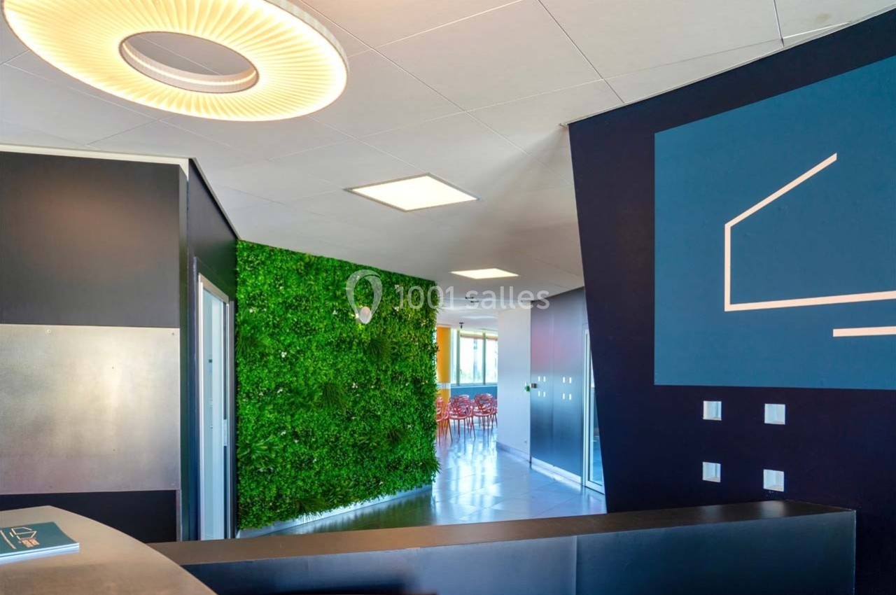 Location salle Caluire-et-Cuire (Rhône) - Le Belvédère #10 Mur végétal dans un espace intérieur moderne avec un comptoir à l'avant-plan et des chaises visibles au fond.