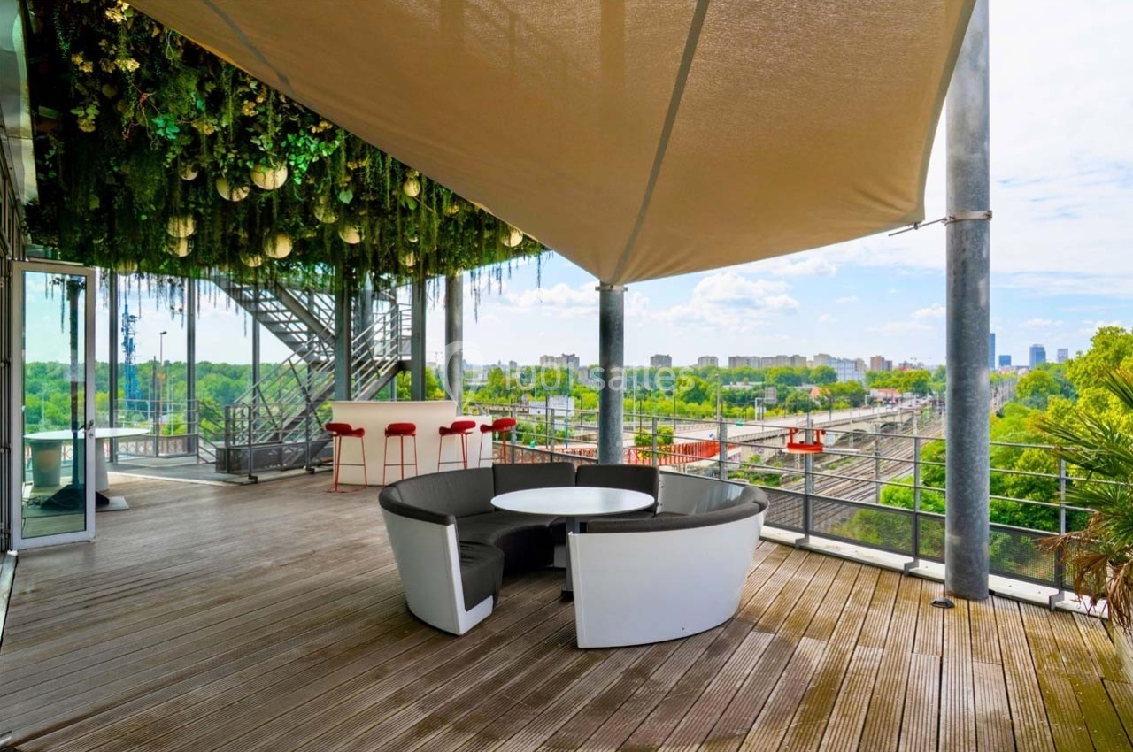 Location salle Caluire-et-Cuire (Rhône) - Le Belvédère #17 Terrasse en bois avec mobilier moderne, vue sur la ville, végétation suspendue et voile d'ombrage.