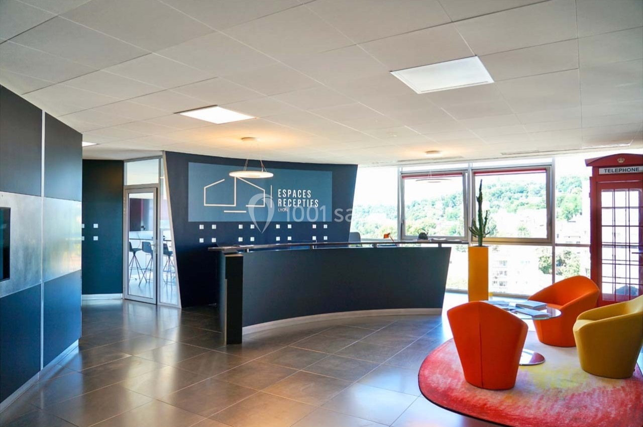 Location salle Caluire-et-Cuire (Rhône) - Le Belvédère #1 Accueil moderne avec comptoir noir, fauteuils colorés, baie vitrée donnant sur un paysage verdoyant.