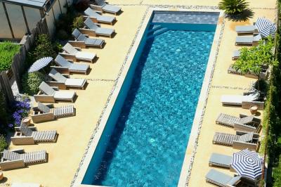 Chambre avec trois lits simples alignés, murs en pierre apparente, plafond en bois et lumière naturelle entrant par une…