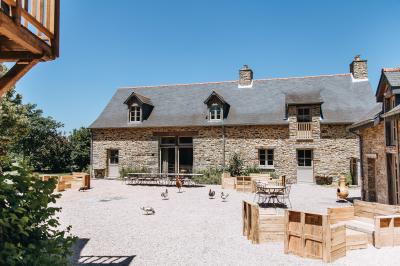 Chambre avec trois lits simples alignés, murs en pierre apparente, plafond en bois et lumière naturelle entrant par une…