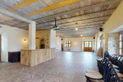 Chambre avec trois lits simples alignés, murs en pierre apparente, plafond en bois et lumière naturelle entrant par une…