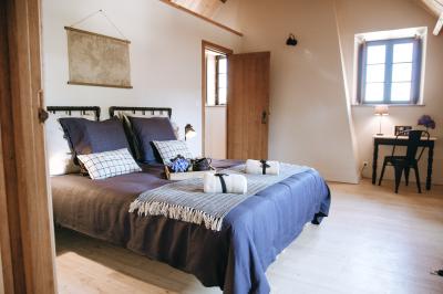 Chambre avec trois lits simples alignés, murs en pierre apparente, plafond en bois et lumière naturelle entrant par une…