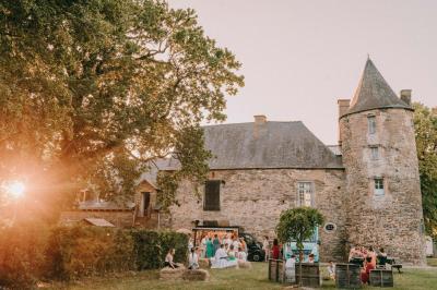 Chambre avec trois lits simples alignés, murs en pierre apparente, plafond en bois et lumière naturelle entrant par une…