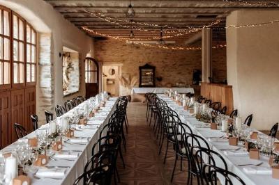 Chambre avec trois lits simples alignés, murs en pierre apparente, plafond en bois et lumière naturelle entrant par une…