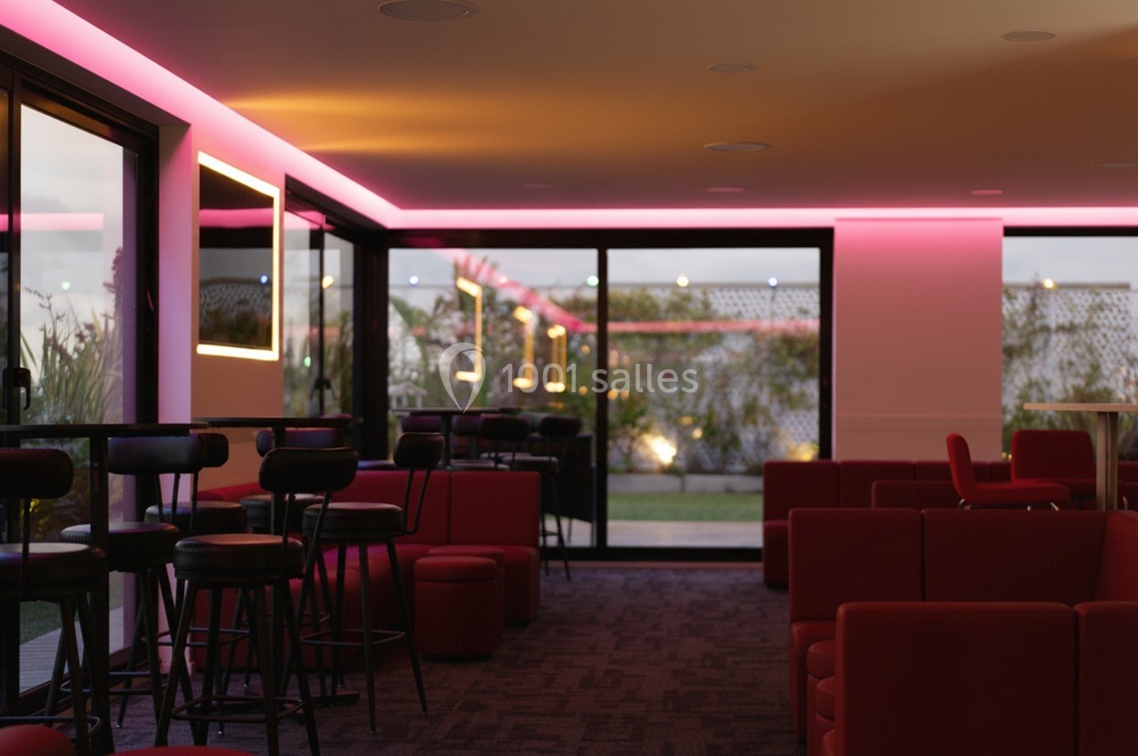 Salle moderne avec éclairage LED rose, mobilier rouge et noir, grandes baies vitrées donnant sur un espace extérieur.