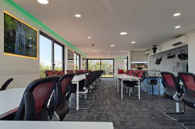 Double lavabo moderne avec robinets chromés, distributeur de savon mural et grand miroir éclairé en arrière-plan.