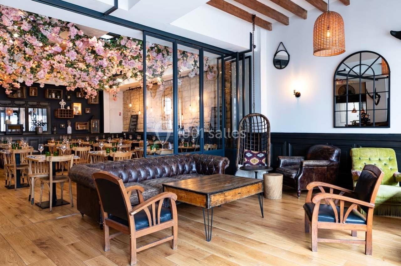 Salon lumineux avec mobilier en bois et cuir, plafond décoré de fleurs, et ambiance chaleureuse dans un espace ouvert.