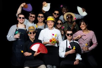 Dessert raffiné présenté dans un bol noir, décoré de fruits rouges, de crème blanche et de touches végétales.