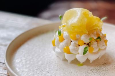 Dessert raffiné présenté dans un bol noir, décoré de fruits rouges, de crème blanche et de touches végétales.