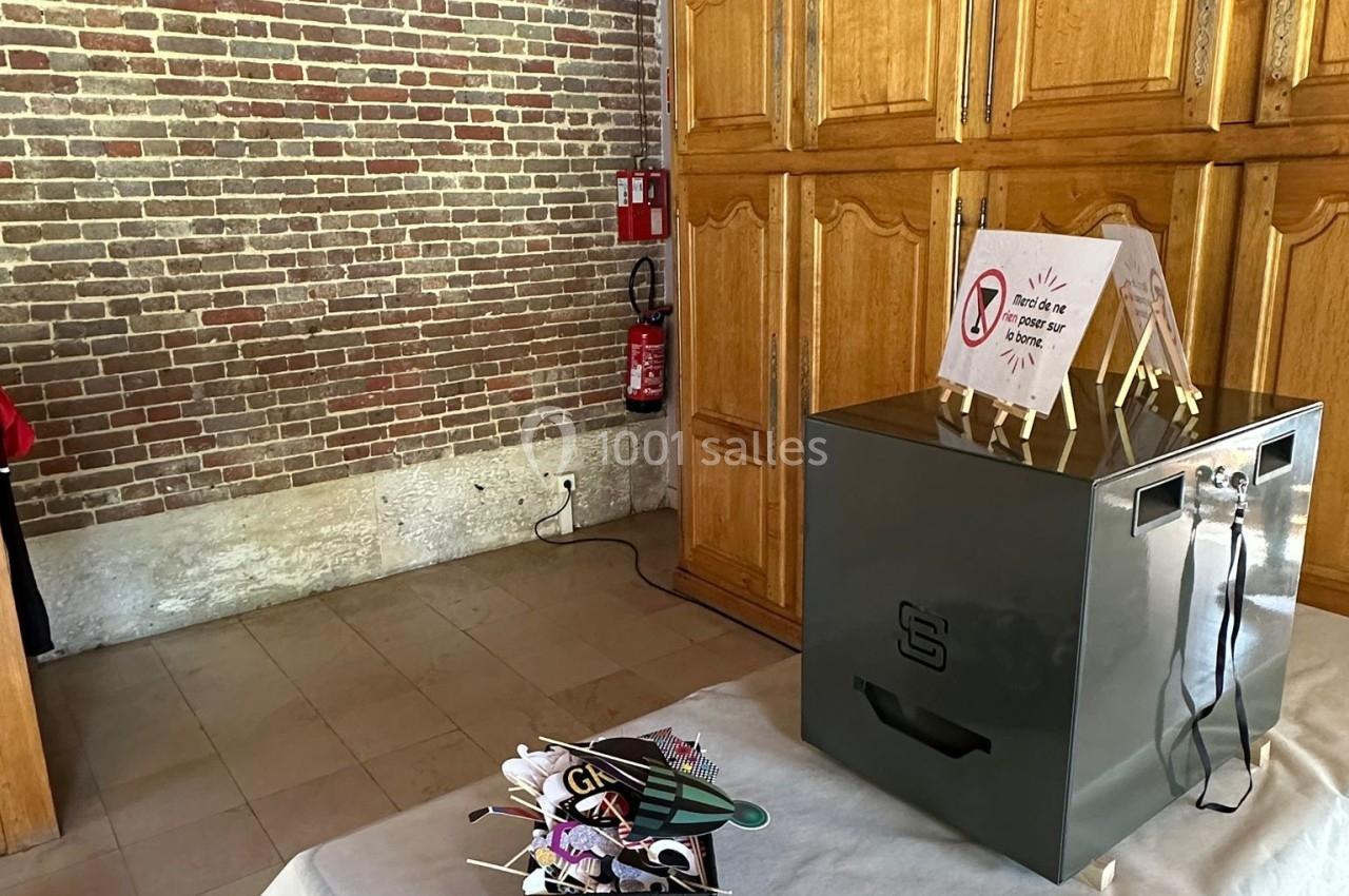 Une table avec une boîte métallique, un panier d'accessoires et un panneau d'instructions dans une pièce en briques.