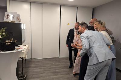 Des personnes dansent et discutent dans une salle éclairée par des lumières colorées lors d'un événement festif.