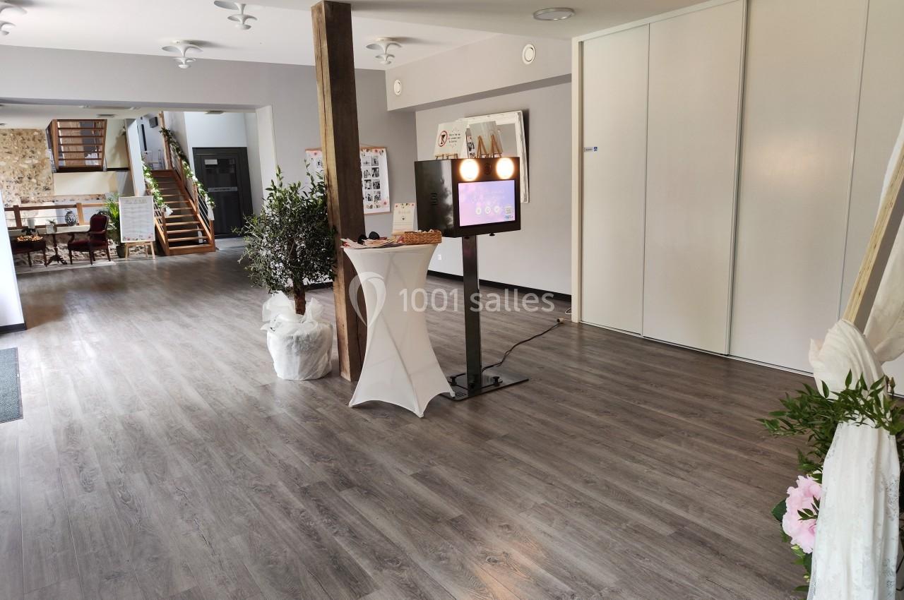 Espace intérieur lumineux avec sol en parquet, borne photo interactive et table haute dans un cadre moderne et épuré.