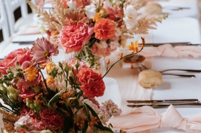 Table décorée avec des fleurs colorées, des fruits et des couverts disposés pour un repas festif.
