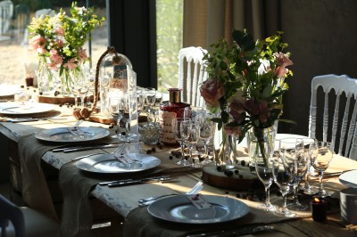 Table décorée avec des fleurs colorées, des fruits et des couverts disposés pour un repas festif.