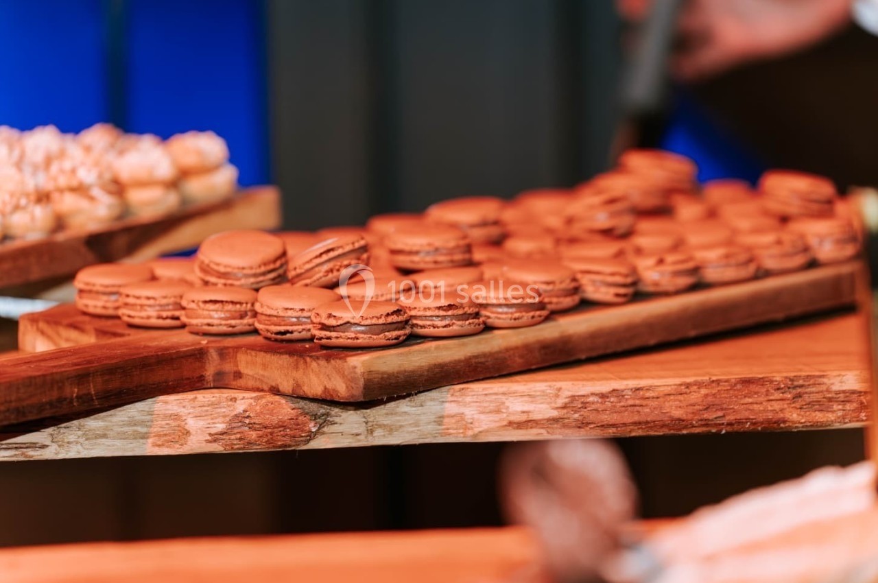 Plateau en bois garni de macarons au chocolat alignés, exposé dans un environnement lumineux.