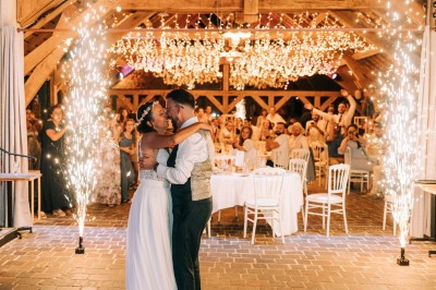 Chambre spacieuse sous combles avec poutres apparentes, lit double, coin salon coloré et grande baie vitrée.