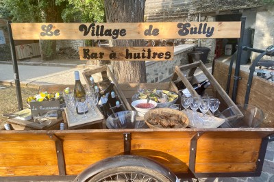 Chambre spacieuse sous combles avec poutres apparentes, lit double, coin salon coloré et grande baie vitrée.