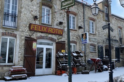 Chambre spacieuse sous combles avec poutres apparentes, lit double, coin salon coloré et grande baie vitrée.