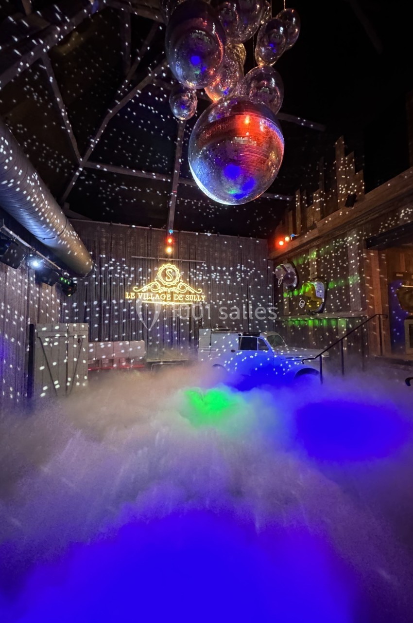 Salle décorée avec des lumières disco, une boule à facettes et un sol recouvert de fumée colorée.