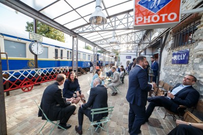 Chambre spacieuse sous combles avec poutres apparentes, lit double, coin salon coloré et grande baie vitrée.