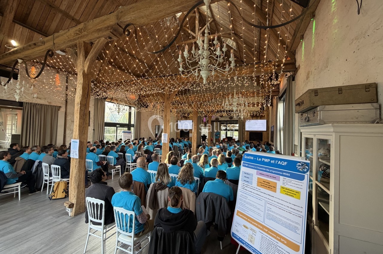 Salle de conférence avec des participants en t-shirts bleus, un écran de présentation et un panneau d'information au premier…
