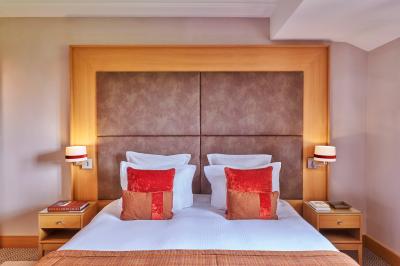 Chambre d'hôtel avec un grand lit double, des oreillers rouges, un éclairage doux et une décoration murale colorée.