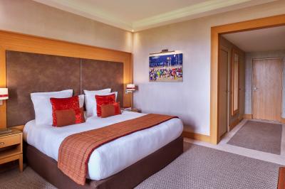 Chambre d'hôtel avec un grand lit double, des oreillers rouges, un éclairage doux et une décoration murale colorée.