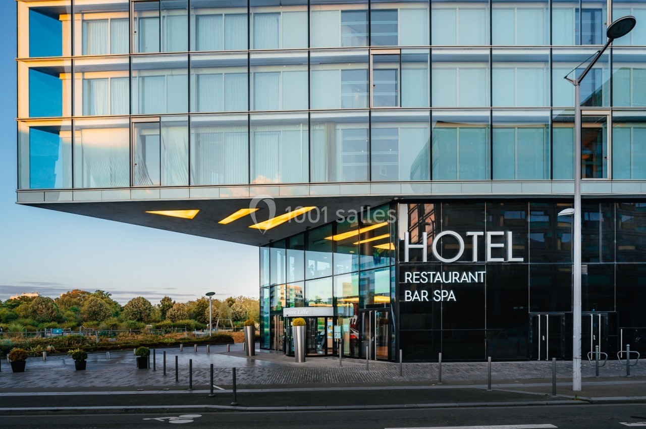 Façade moderne d'un hôtel avec grandes baies vitrées, entrée principale et enseigne indiquant restaurant, bar et spa.