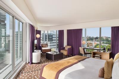 Chambre d'hôtel moderne avec grand lit, bureau, fauteuil, vue sur l'extérieur et salle de bain attenante.