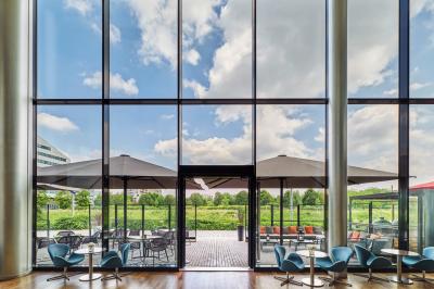 Chambre d'hôtel moderne avec grand lit, bureau, fauteuil, vue sur l'extérieur et salle de bain attenante.