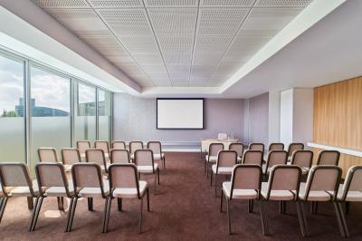Chambre d'hôtel moderne avec grand lit, bureau, fauteuil, vue sur l'extérieur et salle de bain attenante.