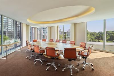Chambre d'hôtel moderne avec grand lit, bureau, fauteuil, vue sur l'extérieur et salle de bain attenante.