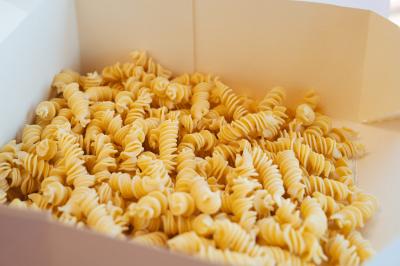 Pâtes fusilli crues dans une boîte en carton ouverte.
