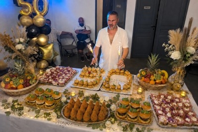Plateau garni de charcuteries, fromage frais, fleurs comestibles et pousses, disposés sur des tranches de pain.