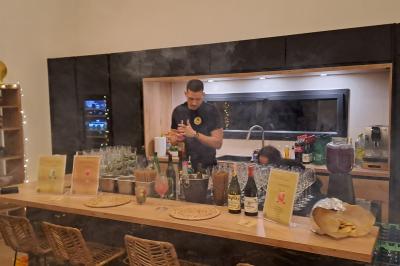 Maison avec terrasse entourée de végétation, située dans un jardin avec allée en gravier et ciel dégagé en arrière-plan.