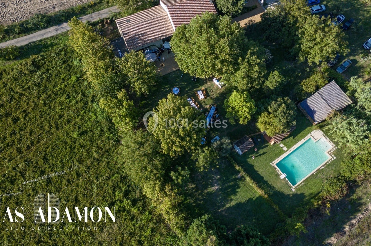 Vue aérienne d'un domaine avec piscine, bâtiments, arbres et espaces verts entourés de végétation.