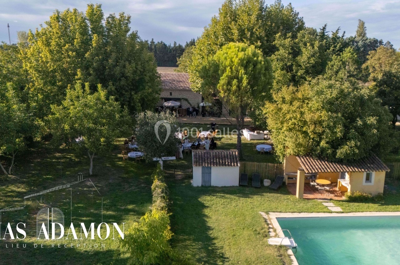 Vue aérienne d'un domaine arboré avec piscine, espaces extérieurs aménagés et bâtiments en arrière-plan.
