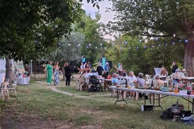 Maison avec terrasse entourée de végétation, située dans un jardin avec allée en gravier et ciel dégagé en arrière-plan.